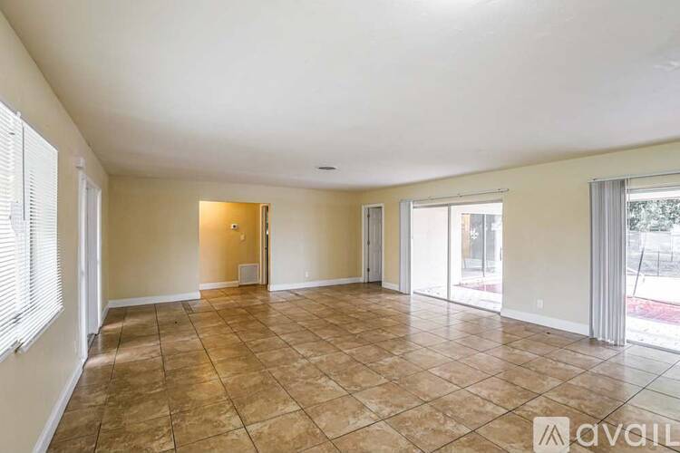 A spacious room with tiled flooring and a sliding glass door.