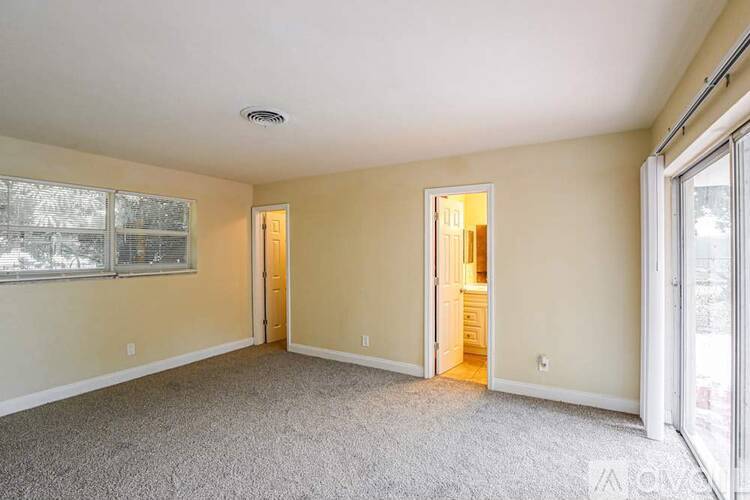 A spacious room with carpeted floor and two open doors.