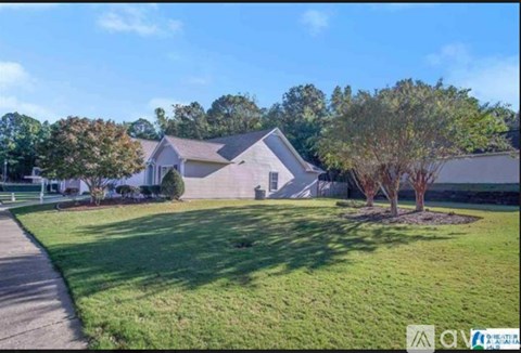A house with a well-maintained lawn and trees in the background.