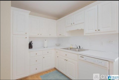 A kitchen with white cabinets and a blue rug on the floor.