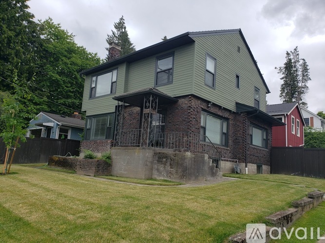 A house with a green siding and a stone wall in front.
