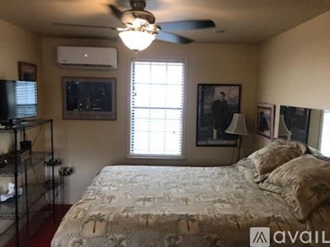 A bedroom with a bed, a ceiling fan, and a window with blinds.