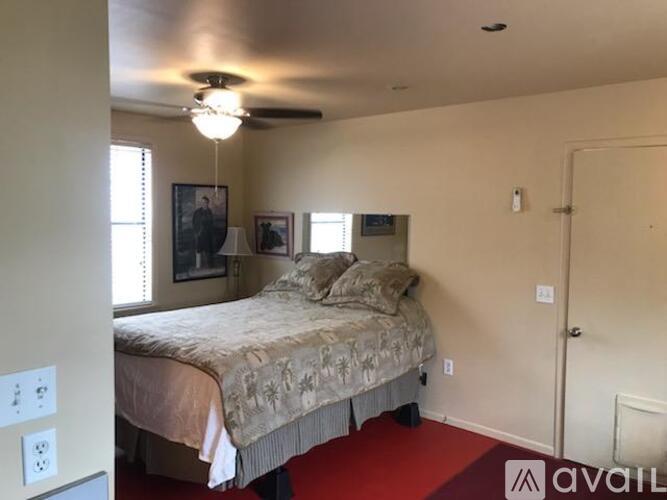A bedroom with a bed, a ceiling fan, and two pictures on the wall.
