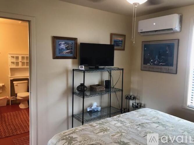 A bedroom with a bed, a television, and a shelf with various items.