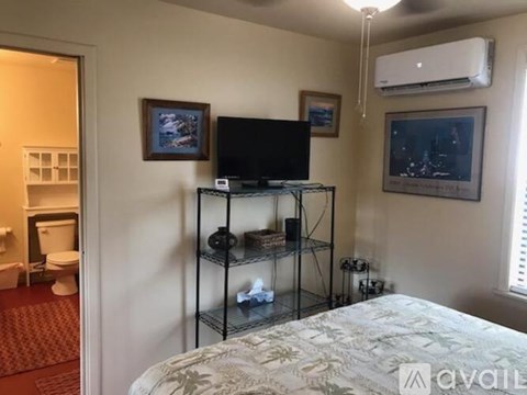 A bedroom with a bed, a television, and a shelf with various items.
