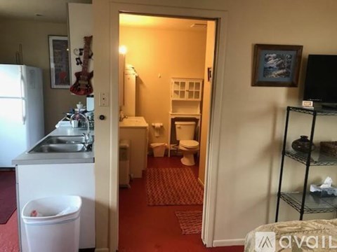 A small kitchen with a refrigerator, sink, and a trash can.