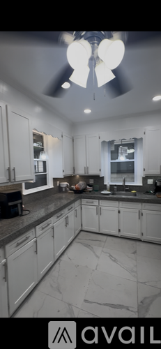 A kitchen with white cabinets and a marble countertop.