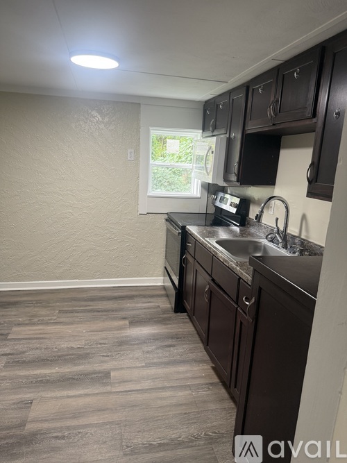 A kitchen with dark brown cabinets and a window.