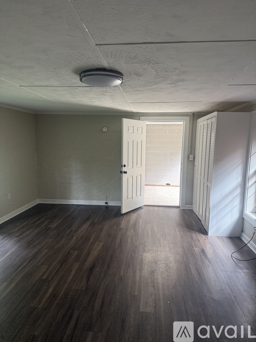 A room with wooden floors and a door leading to another room.