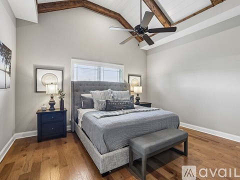 A bedroom with a bed, nightstand, and a bench under a ceiling fan.
