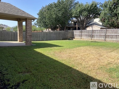 A backyard with a wooden fence and a gazebo.