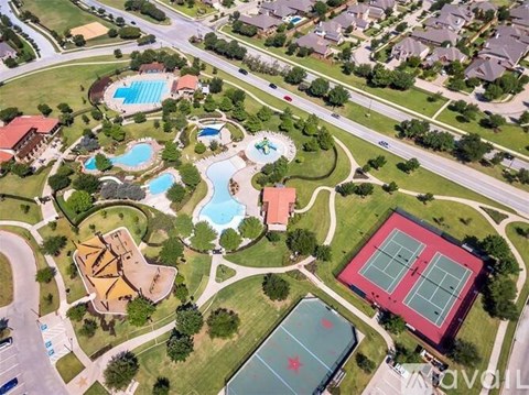 An aerial view of a community with a pool, tennis courts, and a basketball court.
