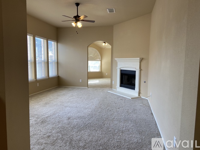 A living room with a fireplace and a ceiling fan.