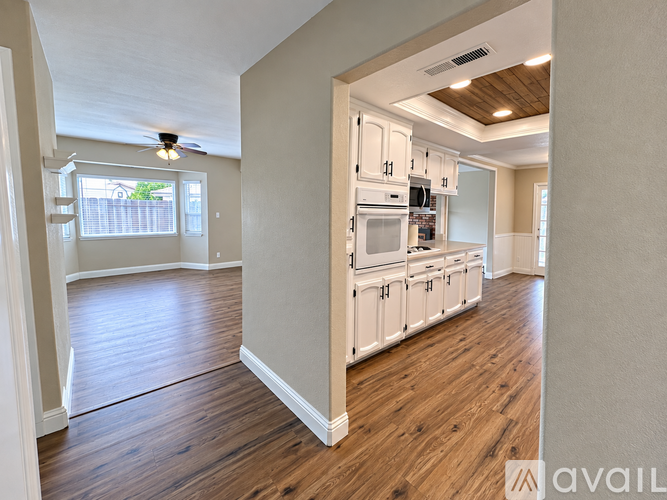 A kitchen with white cabinets and a wooden floor.