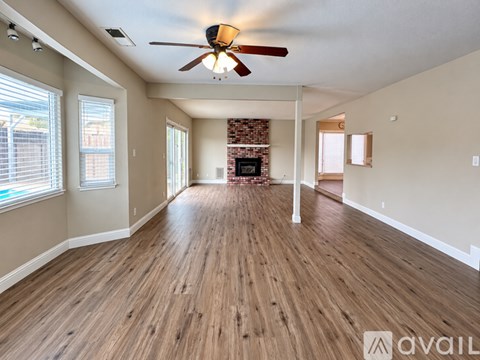 A spacious room with wooden floors and a ceiling fan.