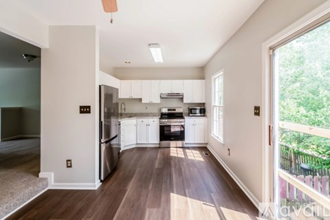 A kitchen with white cabinets and a wooden floor.