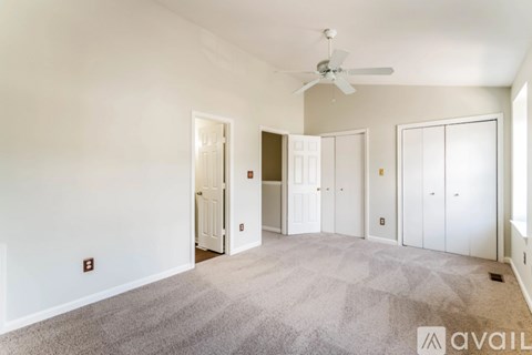 A spacious room with a fan and carpeted floor.