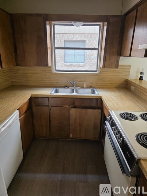 A kitchen with wooden cabinets and a window above the sink.