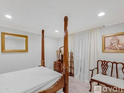 A bedroom with a four poster bed and a chair.