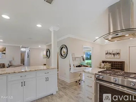 A modern kitchen with white cabinets and a stainless steel range hood.