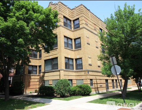 A large brown building with a lot of windows and a tree in front.