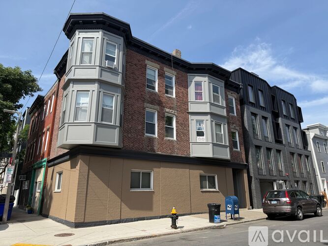 A street view of a multi-story building with a car parked in front.