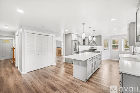 A modern kitchen with white appliances and wooden floors.