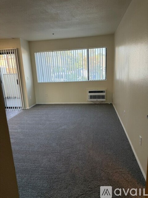 A room with a carpeted floor and a window with blinds.