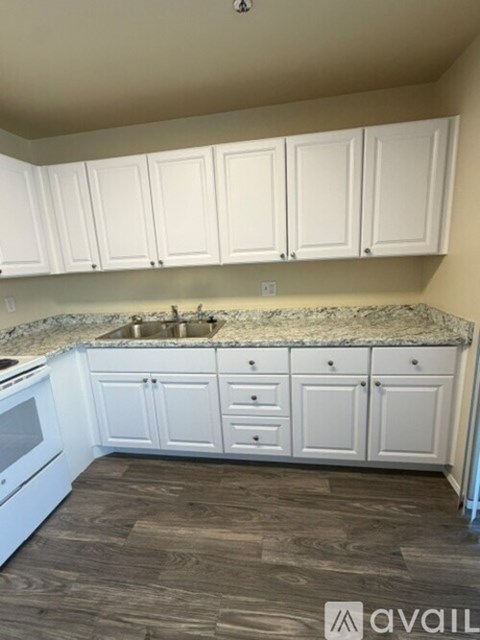 A kitchen with white cabinets and a granite countertop.