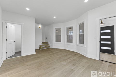 A spacious room with wooden flooring and white walls.