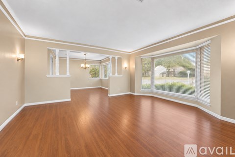 A spacious room with wooden floors and white trim.