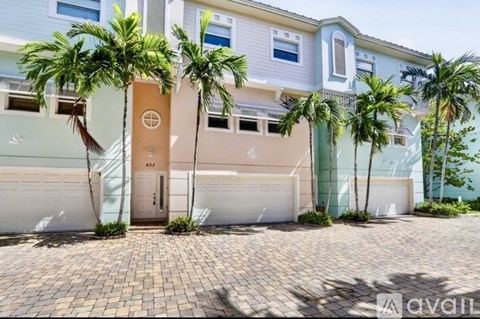 A row of houses with garages and palm trees in front.