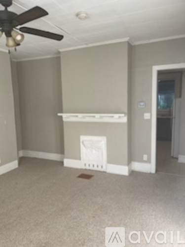 A room with a ceiling fan and a white shelf.