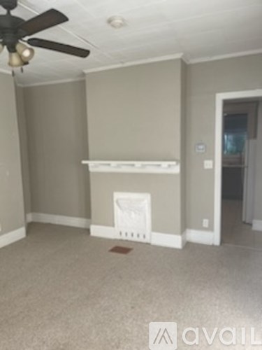 A room with a ceiling fan and a white shelf.