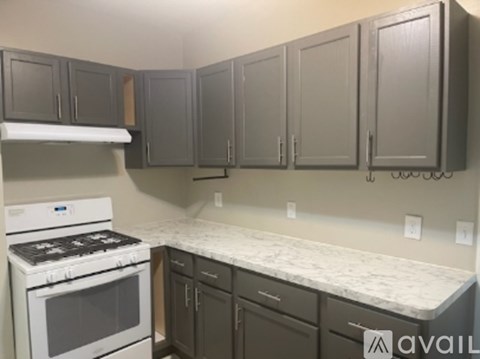 A kitchen with a white stove top oven and a marble counter top.