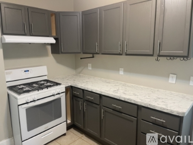 A kitchen with a white stove top oven and a white counter top.