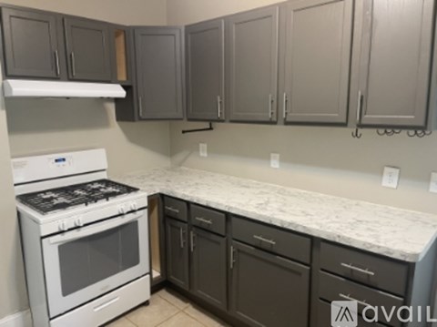 A kitchen with a white stove top oven and a white counter top.