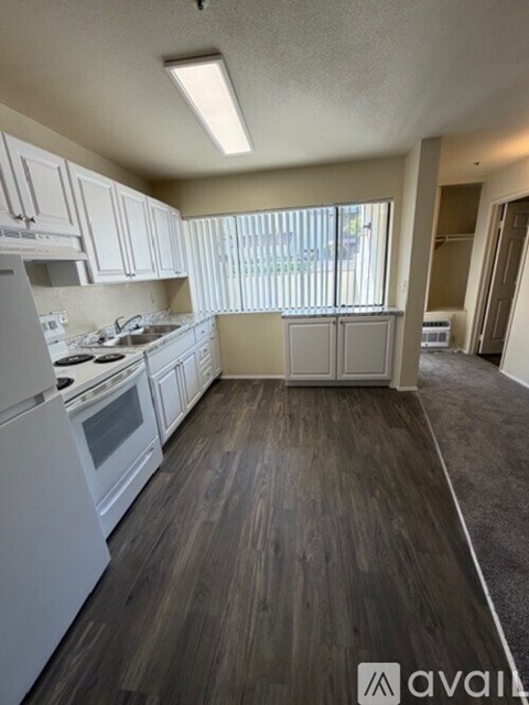 A kitchen with white appliances and wooden floors.