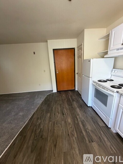 A kitchen with white appliances and a wooden door.