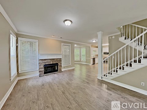 A spacious living room with a fireplace and a staircase.