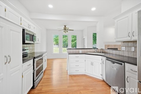 A kitchen with white cabinets and a black countertop.