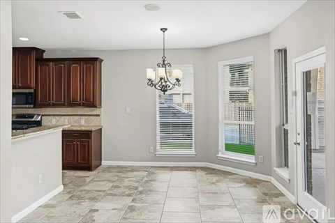 A kitchen with brown cabinets and a chandelier hanging from the ceiling.