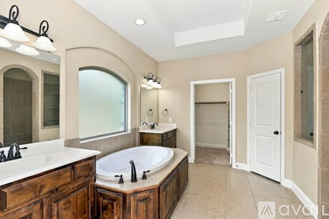 A bathroom with a large tub and double sinks.