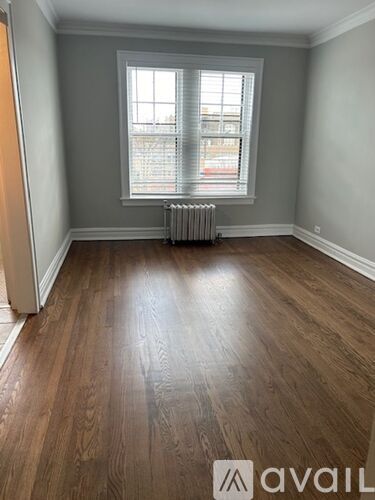 A room with wooden flooring and a window with blinds.