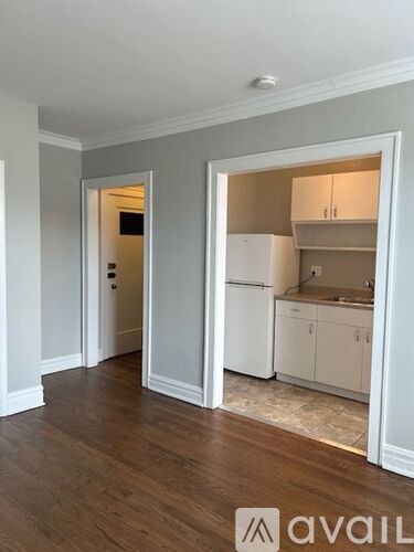 A kitchen with white appliances and cabinets is visible through an open doorway.