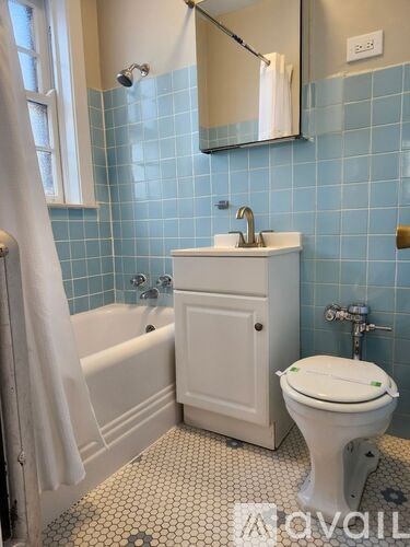 A white toilet sits in a bathroom with blue tiles.