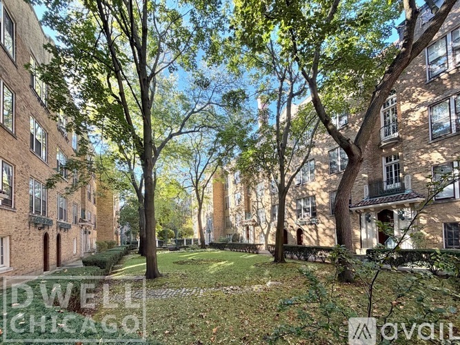 A tree-lined pathway leads to a brick building.
