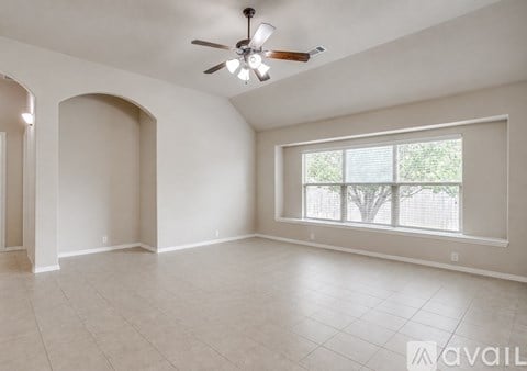 A spacious room with a ceiling fan and a large window.