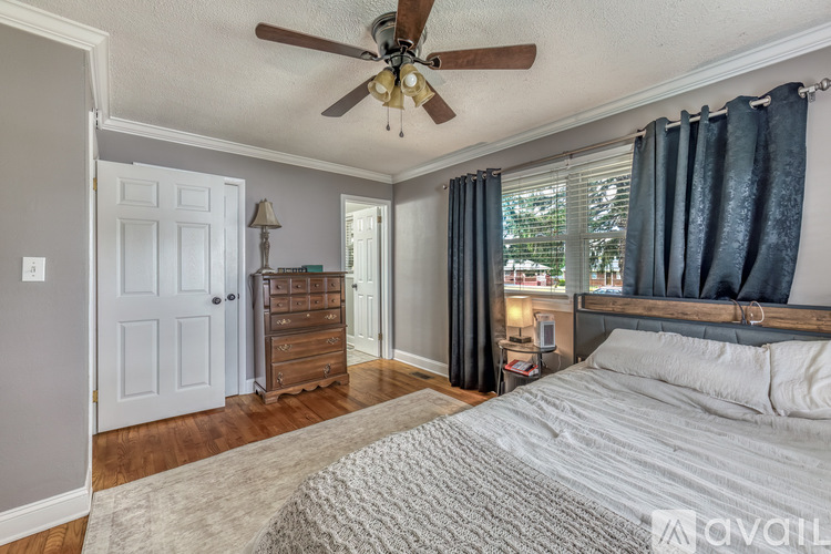 A bedroom with a bed, dresser, and window with curtains.