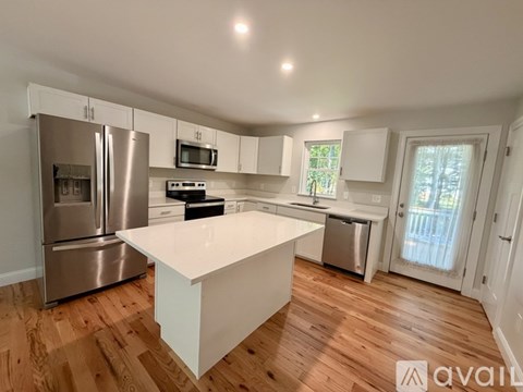 A kitchen with a white island and stainless steel appliances.